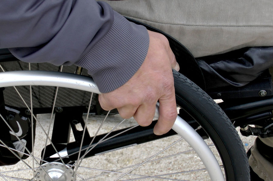 dłoń zaciśnięta na kole wózka inwalidzkiego