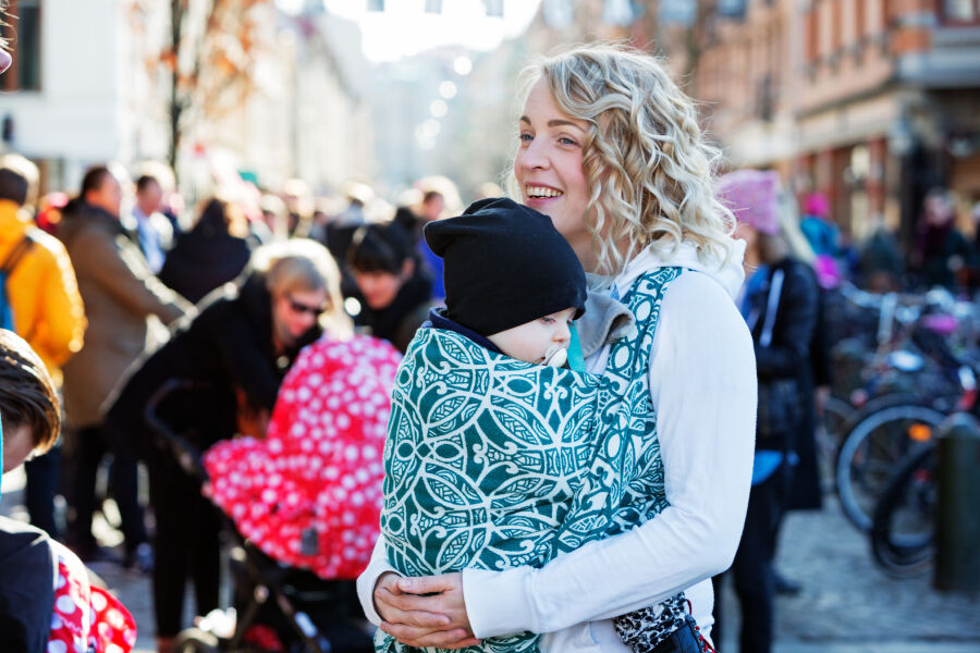 Göteborg - matka z małym dzieckiem w chuście na spacerze na ulicy miasta 