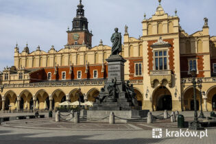 Zdjęcie przedstawia pomnik Adama Mickiewicza na tle krakowskich Sukiennic.