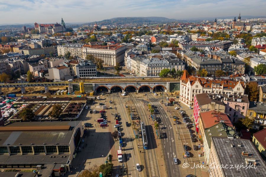 Zdjęcie przedstawiające  widok z drona na Halę Targową w Krakowie wraz z estakadą kolejową i kamienicami przy ul. Grzegórzeckiej.