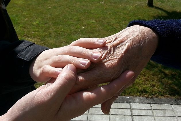 dwie trzymające się dłonie osoby starszej i młodej