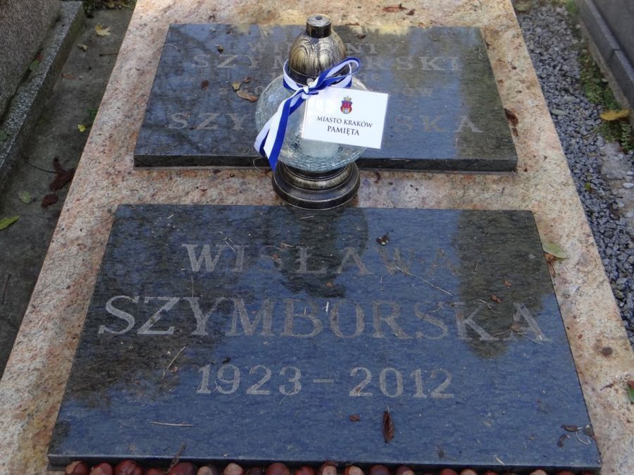 Na zdjęciu widać tablicę nagrobną Wisławy Szymborskiej (1923-2012) oraz znicz przepasany biało-niebieską wstążką z karteczką z napisem 