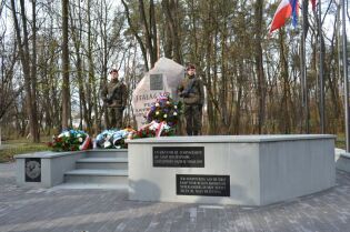 Pomnik w kształcie głazu z tablicami w języku francuskim i polskim. Po obu stronach pomnika stoją polscy żołnierze z bronią, na maszcie flaga Polski i Unii Europejskiej, przy pomniku leżą wieńce 
