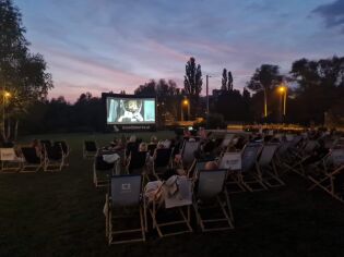 Noc Perseidów w Zesławicach - inicjatywa lokalna. Ludzie siedzący na leżakach oglądający kino plenerowe.