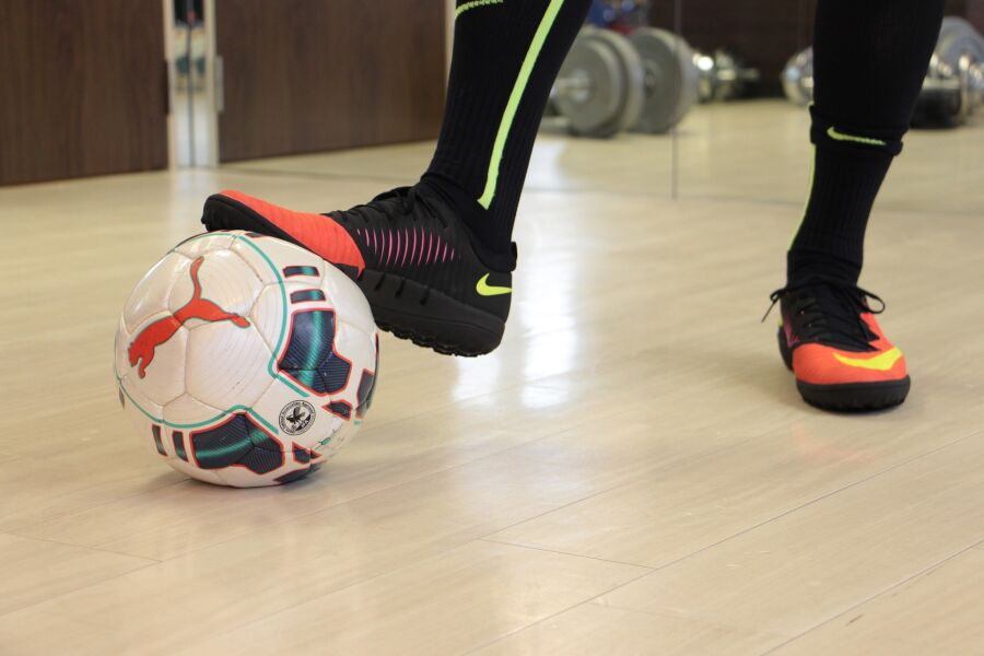 Zdjęcie przedstawia piłkę na której spoczywa noga piłkarza