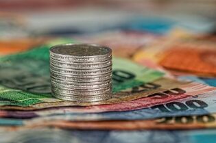 Zdjęcie przedstawia wielobarwne banknoty, na których stoi wieżyczka z monet.. Fot. Pixabay: Stevepb