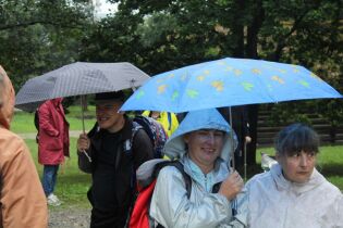 Grupa kobiet i mężczyzn w plenerze pod parasolami