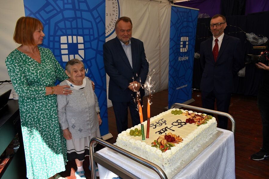 Pan Prezydent Sndrzej Kulig, Dyrektor Domu Pan Tomasz Gniadek, Mieszkanka i Pracownik Domu stoją przed jubileuszowym tortem.