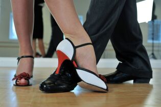 Grafika przedstawia stopy tancerzy, tańczących tango.