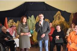 Dyrektor Domu i Prezes Stowarzyszenia witają Gości. Z tyłu siedzą aktorzy.