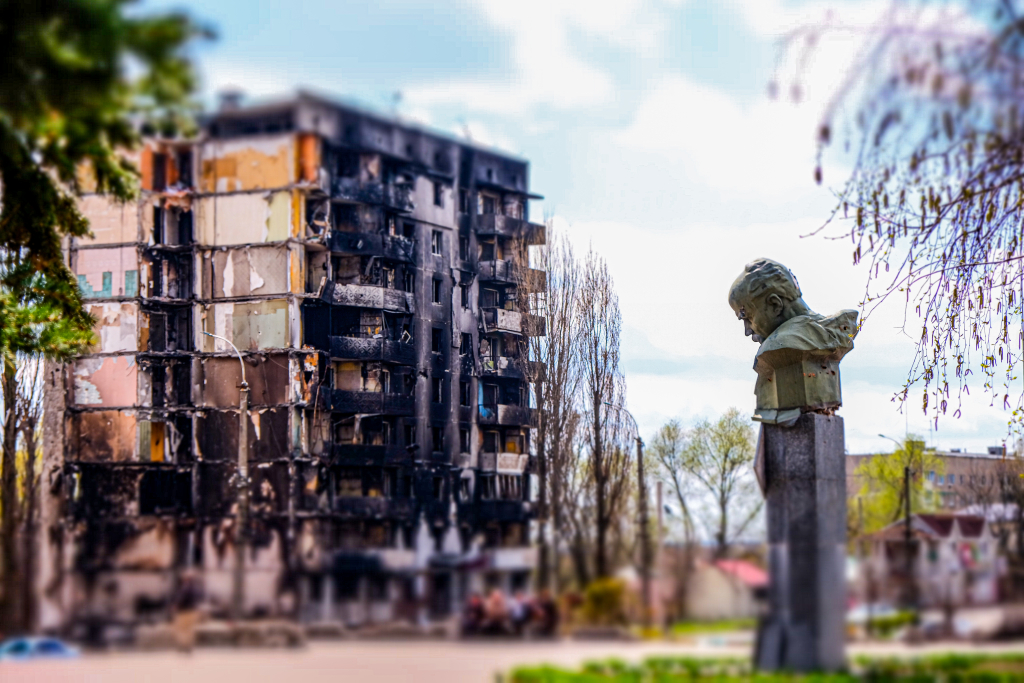 Zachowany pomnik ukraińskiego poety Tarasa Szewczenki na tle zniszczonego bombą lotniczą bloku