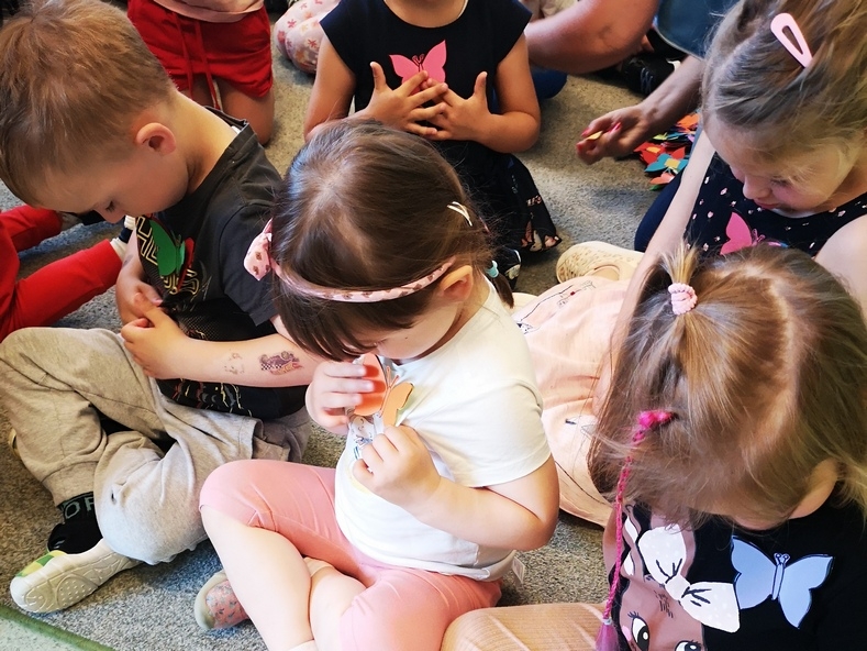 Dzieci przyglądające się motylkowym przypinkom na ich ubrankach