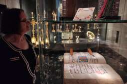 Na zdjęciu mieszkanka wpatruje się w różne przedmioty liturgiczne. 