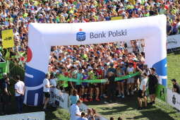 Zdjęcie przestawia start 18. PKO Biegu Trzech Kopców. W tle widać panoramę miasta oraz uczestników biegu stojących na starcie.