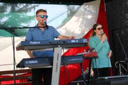 Dwoje muzyków występuje na scenie – mężczyzna gra na keyboardzie, a kobieta śpiewa do mikrofonu.