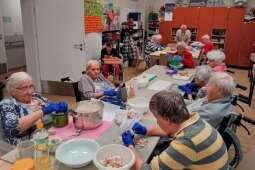 Na zdjęciu Mieszkanki przy stołach, przygotowujące składniki do zrobienia pizzy.