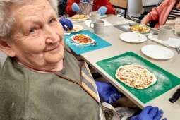 Na zdjęciu uśmiechnięta Mieszkanka z przygotowaną przez siebie pizzą, tuż przed włożeniem do pieca.