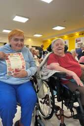 Na zdjęciu mieszkanki siedzące na wózkach wraz z dyplomem za udział w konkursie "Jesienny bukiet" organizowanym przez DPS im. Jana Pawła II w Krakowie