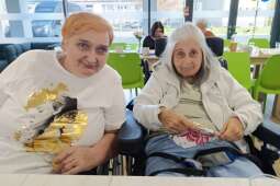 Na zdjęciu uśmiechnięte Mieszkanki siedzą przy stole podczas urodzinowego poczęstunku