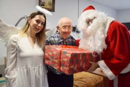 Mieszkaniec z prezentem wraz z Mikołajem i aniołkiem