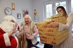 Roześmiana Mieszkanka wraz z Mikołajem i aniołkiem trzymającym prezent