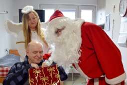 Mieszkaniec zerkający do torby prezentowej w towarzystwie aniołka i Mikołaja