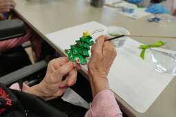 Na zdjęciu Mieszkanka maluje figurkę gipsową (choinkę). 