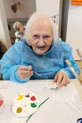 Na zdjęciu uśmiechnięta Mieszkanka, której ogromną radość sprawia malowanie figurki gipsowej (gwiazdy). 