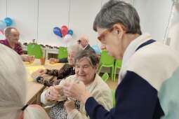 Na zdjęciu Mieszkanka podchodzi do współmieszkanki, by złożyć życzenia podczas toastu. 