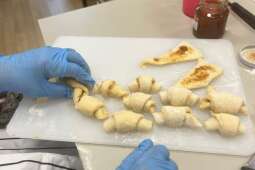 Na zdjęciu Mieszkanka formuje rogaliki z ciasta drożdżowego.