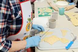 Na zdjęciu Mieszkanka kroi odpowiednie fragmenty ciasta drożdżowego na rogaliki.