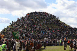 Tłum ludzi zgromadzony u stóp i na Kopcu Krakusa podczas wydarzenia plenerowego. Słoneczny dzień, jasne niebo. Uczestnicy obserwują wydarzenia i spacerują po terenie, tworząc żywą, otwartą przestrzeń.