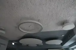 Sufit z okrągłymi lampami i teksturowaną powierzchnią.