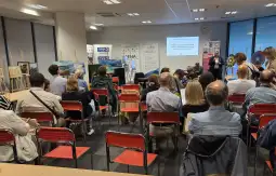 Spotkanie z prelegentem, uczestnicy siedzą na krzesłach w sali konferencyjnej.