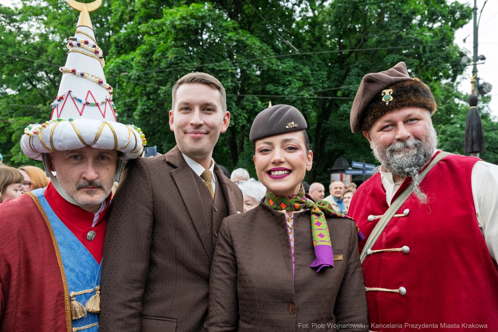 Cztery osoby w strojach historycznych, uśmiechające się na tle zieleni.  Autor: Piotr Wojnarowski