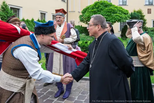 Uczestnicy wydarzenia historycznego witają się, ubrani w stroje z epoki.