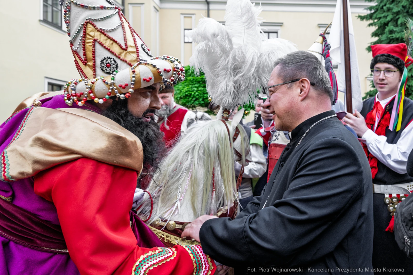 Mężczyzna w tradycyjnym stroju rozmawia z innym mężczyzną w garniturze. W tle widoczni uczestnicy wydarzenia.  Autor: Piotr Wojnarowski