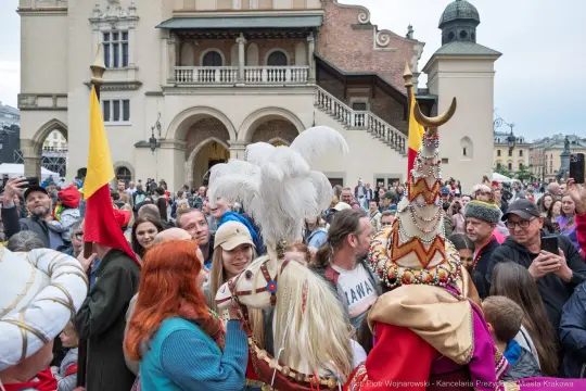 Tłum ludzi w tradycyjnych strojach na tle historycznego budynku.