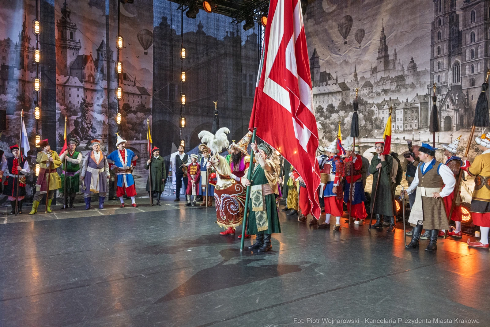 Uczestnicy wydarzenia w strojach historycznych z flagą w centrum sceny.  Autor: Piotr Wojnarowski