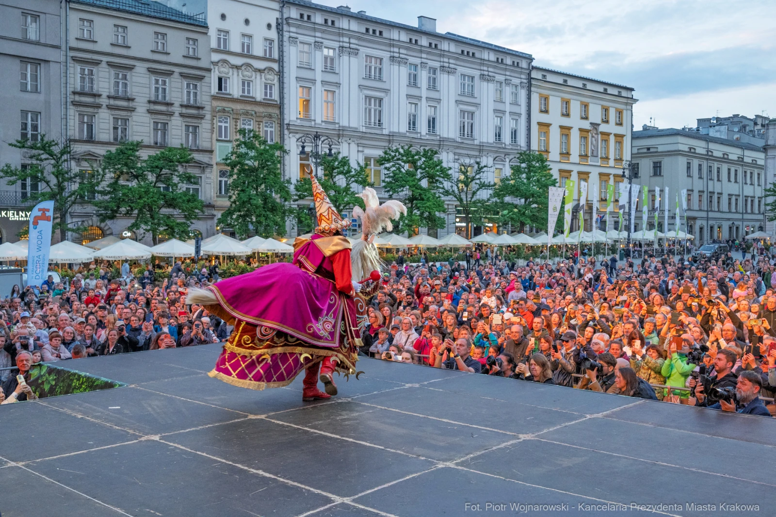 Tancerz w kolorowym stroju występuje przed dużą publicznością na krakowskim rynku.  Autor: Piotr Wojnarowski