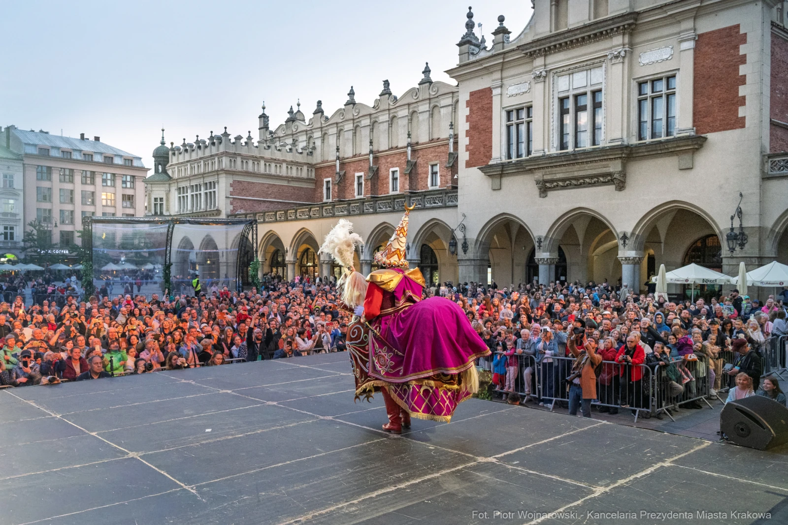 Tłum ludzi na rynku w Krakowie, artysta w kolorowym stroju tańczy na scenie.  Autor: Piotr Wojnarowski