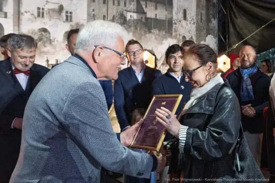 Wręczenie nagrody w uroczystej atmosferze, z uśmiechami i gratulacjami.