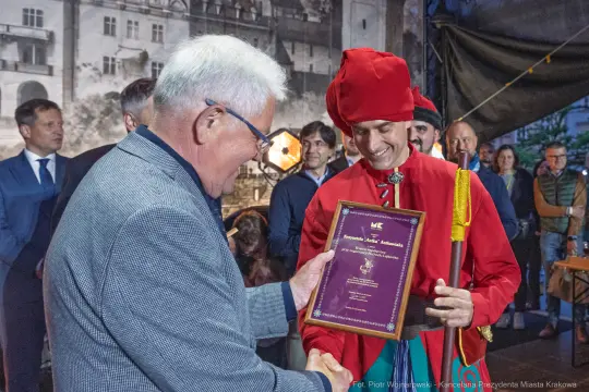 Wręczenie nagrody w historycznych strojach na tle miejskiej scenerii.