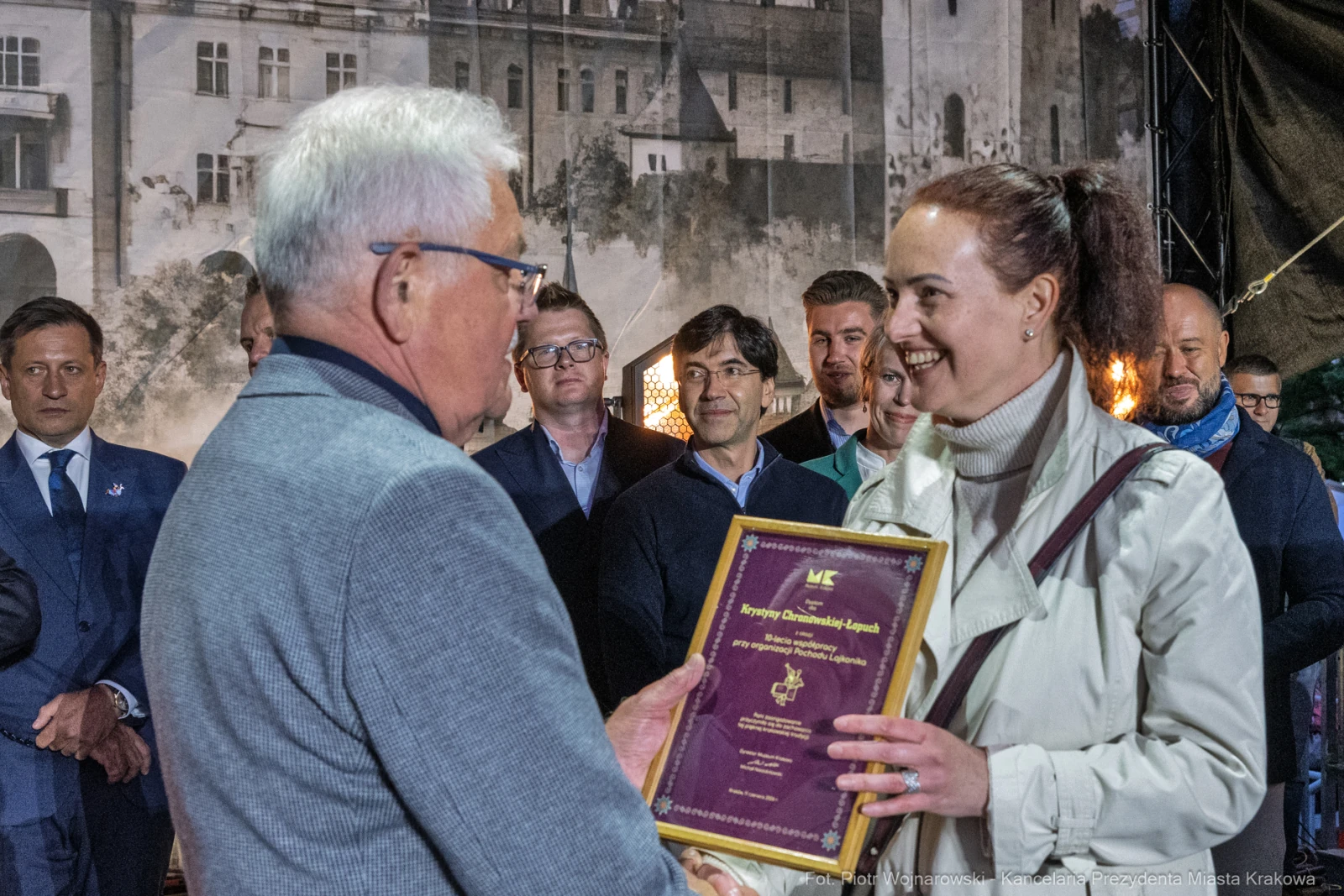 Wręczenie nagrody przez mężczyznę kobiecie na tle miejskiego krajobrazu.  Autor: Piotr Wojnarowski