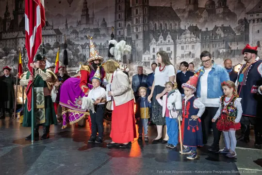 Uczestnicy wydarzenia kulturalnego w tradycyjnych strojach, z flagami i dekoracjami.