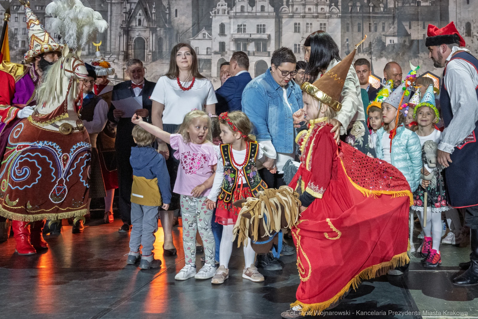 Grupa dzieci i dorosłych w tradycyjnych strojach, uczestniczących w wydarzeniu kulturalnym.  Autor: Piotr Wojnarowski