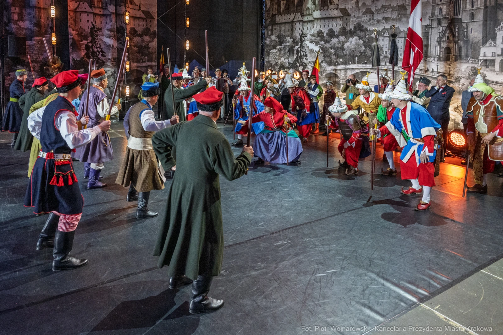 Scena z historycznego przedstawienia z postaciami w strojach z epoki, trzymającymi broń i flagi.  Autor: Piotr Wojnarowski