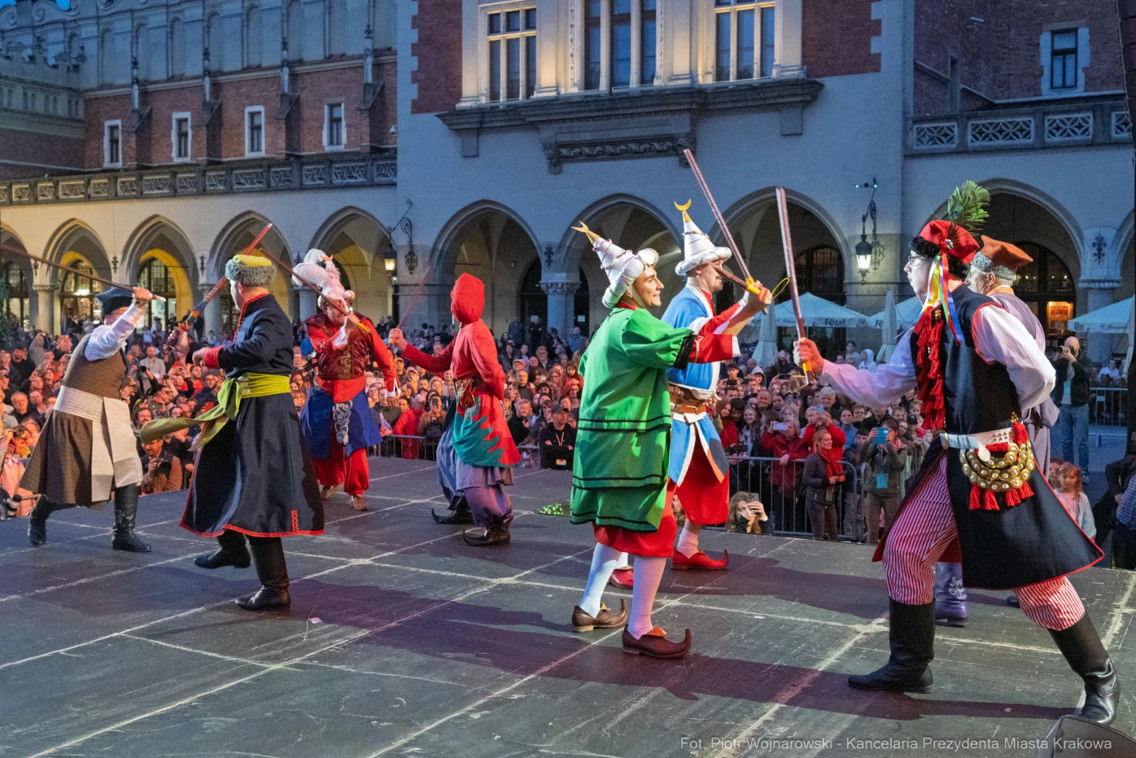 Tradycyjny taniec ludowy z udziałem tancerzy w kolorowych strojach na scenie.  Autor: Piotr Wojnarowski