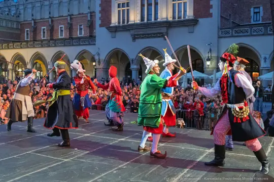 Tradycyjny taniec ludowy z udziałem tancerzy w kolorowych strojach na scenie.