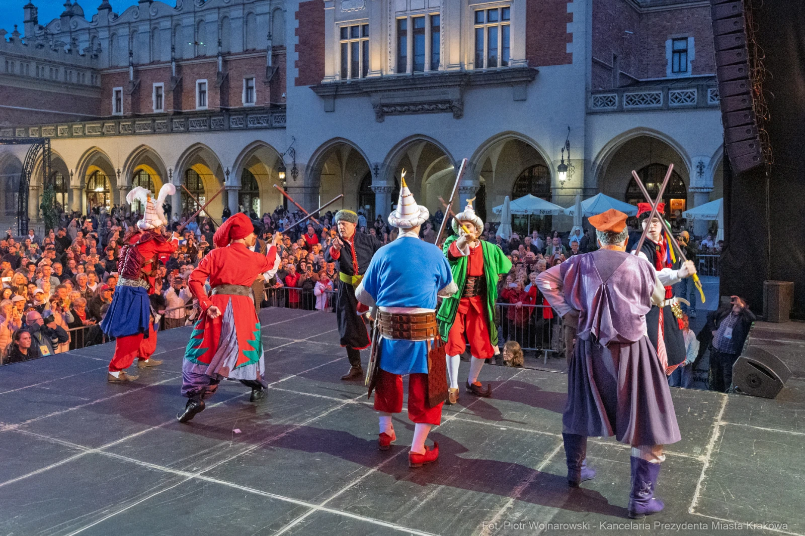 Grupa tancerzy w tradycyjnych strojach podczas występu na scenie w tłumie.  Autor: Piotr Wojnarowski